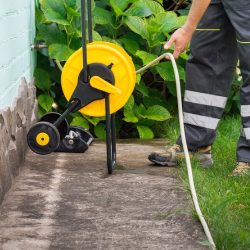 Man preparing a garden hose to water plants and foundation of the house